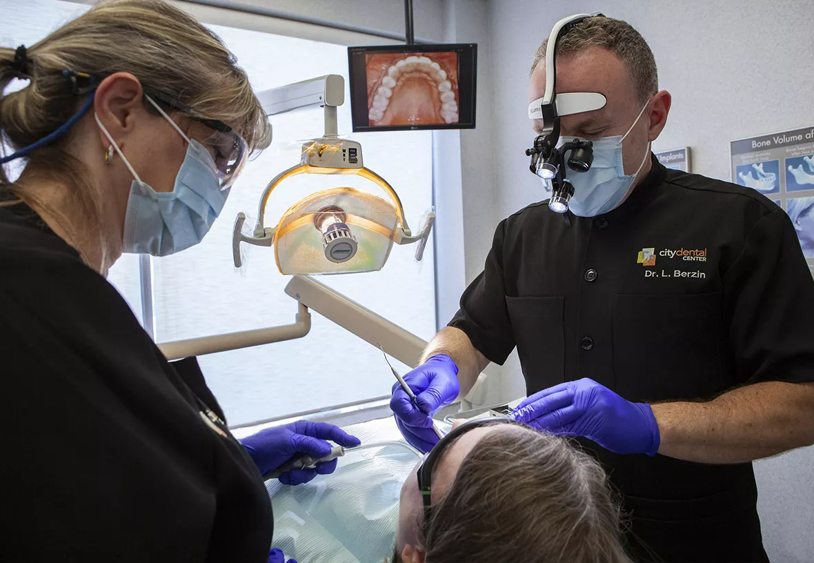 Dr Berzin working with a patient and dental assistant